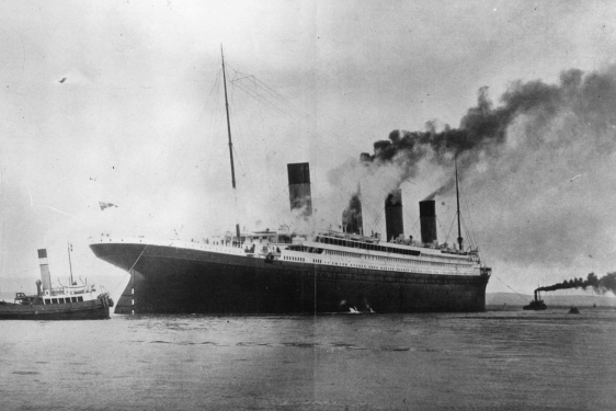 black and white photo of ship and tugs